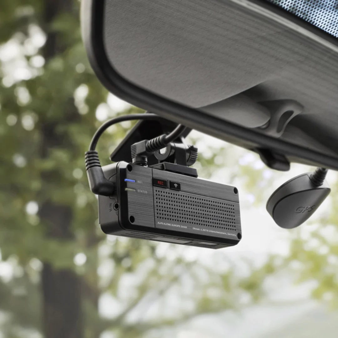 Dash cam DEMIN terpasang di kaca depan mobil mewah sebagai hero shot, lensa menghadap kamera dengan tajam, background interior kabin luxury ter-blur lembut
