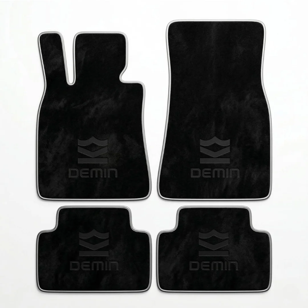 Set karpet dasar mobil premium DEMIN berbahan velour hitam tebal dengan border perak dan logo DEMIN emboss, difoto di atas background studio putih